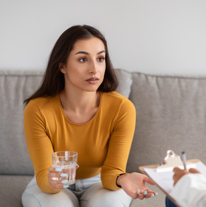 woman sitting at table talking to therapist during detox
